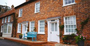 Brick terraced houses with white framed windows and a blue bench out front