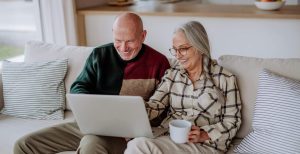 A couple aged 50+ sitting on the sofa looking at their laptop
