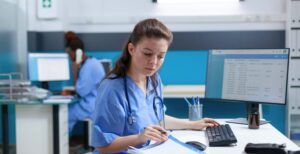 An NHS doctor looking through her notes while sitting at her desk in a hospital