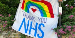 A banner hung from a wall with a rainbow painted on it and the words 'Thank You NHS'.