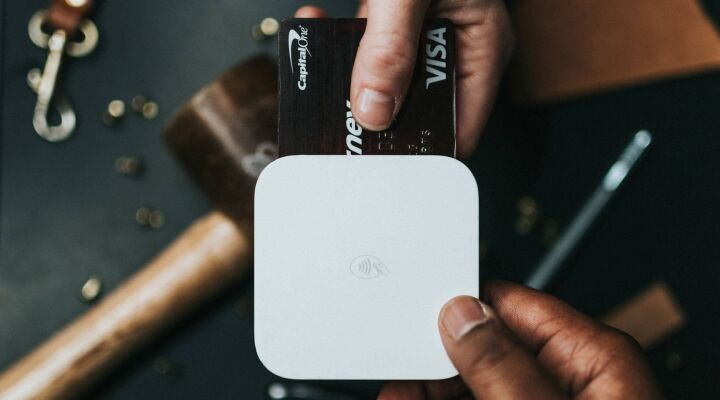 Person holding a Visa credit card and card reader
