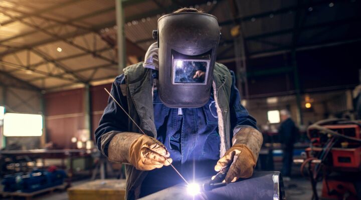 A man weltering a metal sculpture at a table