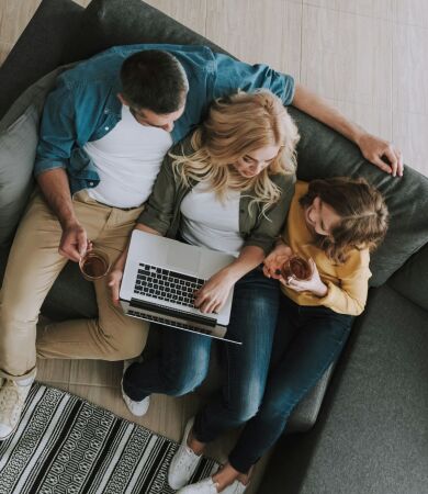 Family sitting on the sofa using a laptop