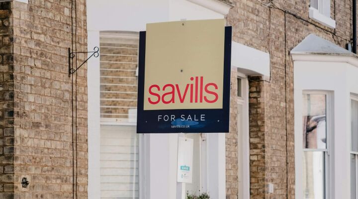 A 'for sale' sign outside a brick house