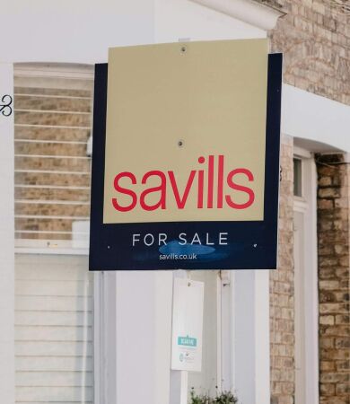 A 'for sale' sign outside a brick house