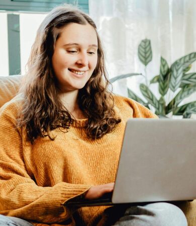 A woman sitting on the sofa looking at her laptop