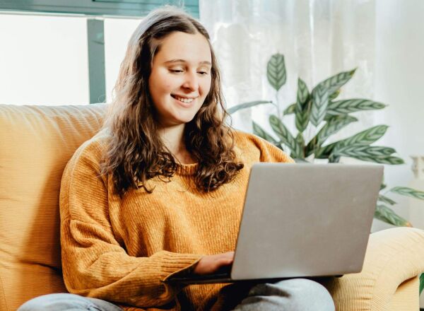 A woman sitting on the sofa looking at her laptop
