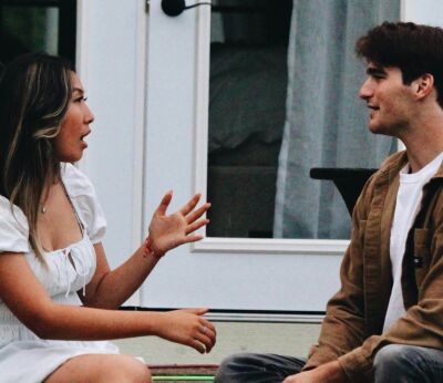 A couple talking to each other while sitting on the decking outside of their house