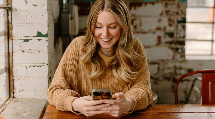 A woman smiling while looking down at her phone
