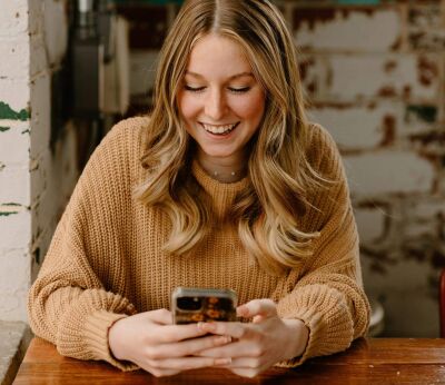 A woman smiling while looking down at her phone