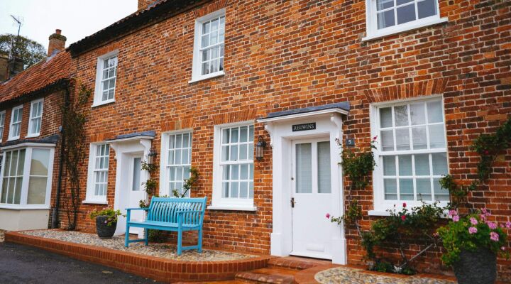 Brick terraced houses with white framed windows and a blue bench out front