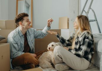 A man passing the keys to his partner in their new house with moving in boxes all around the room