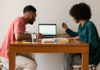 Couple sitting at table working something out on a laptop