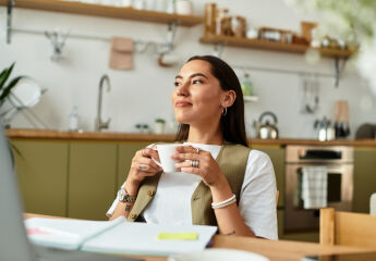 A woman sitting and having a cup of tea in her kitchen
