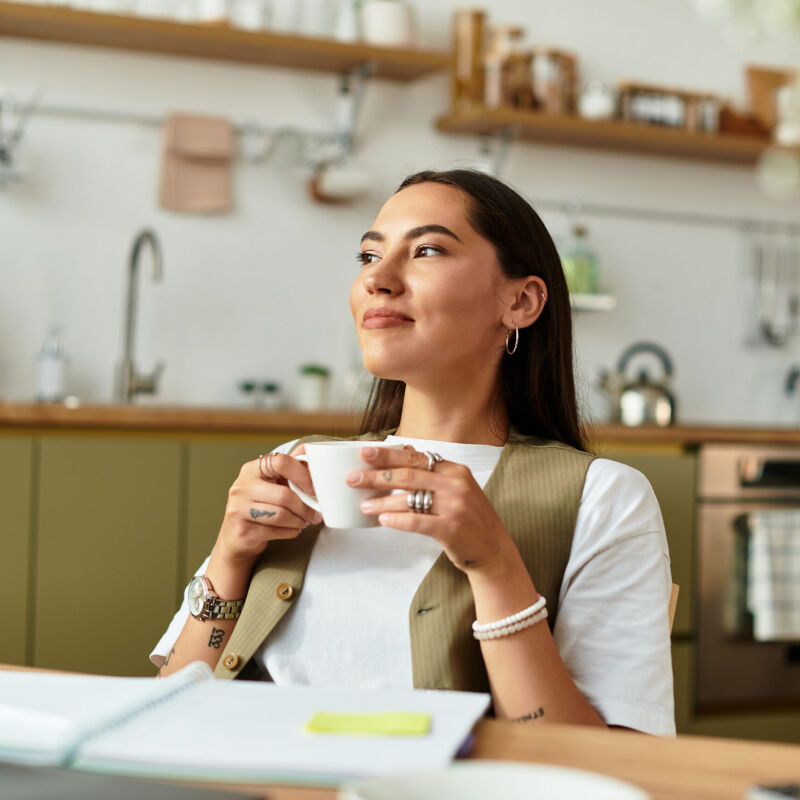 A woman sitting and having a cup of tea in her kitchen