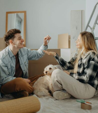 A man passing the keys to his partner in their new house with moving in boxes all around the room