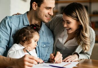 A young couple doing colouring with their baby at the kitchen table