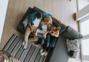 Top view portrait of a family sitting on couch and watching videos on laptop they drinking tea and chatting