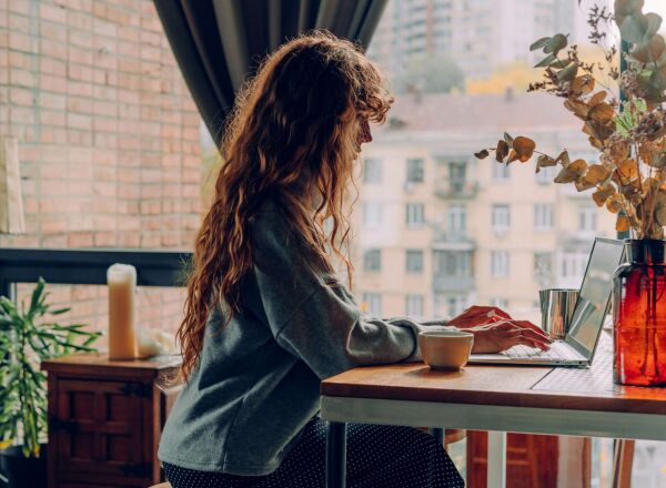 A women sitting in her kitchen working on her laptop
