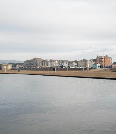 A large body of water with houses in the background on the shore