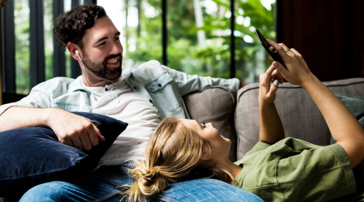 Couple sitting on the sofa looking at a phone