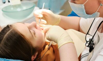 A female dentist using tools to examine the teeth of a young girl