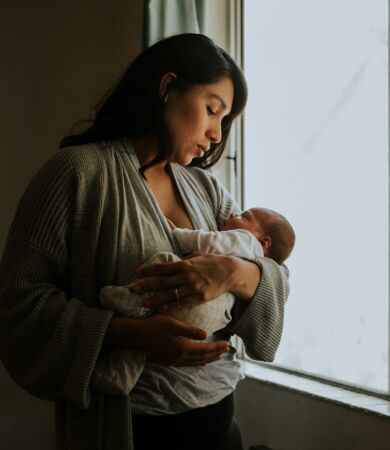 A mum holding her newborn baby by a window