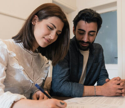 A young couple sitting at a table signing a mortgage